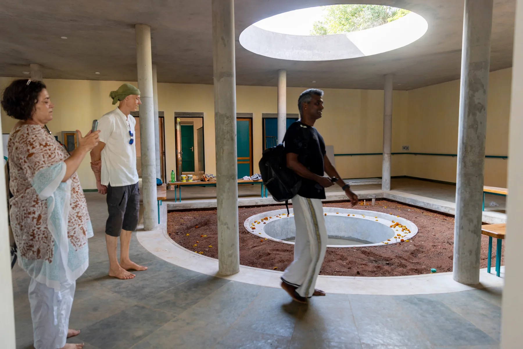 A courtyard inside the building, open to the sky, with a round pool set in red earth