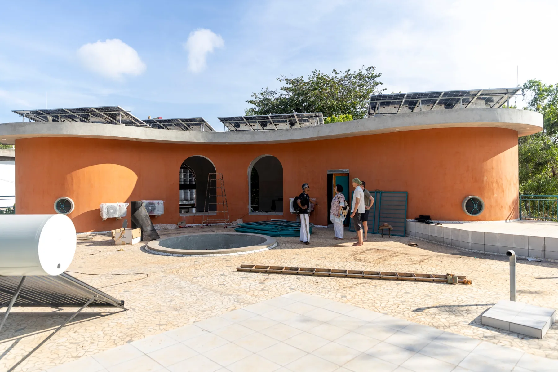 The curving terracotta upper floor of the building, with solar panels along the roof