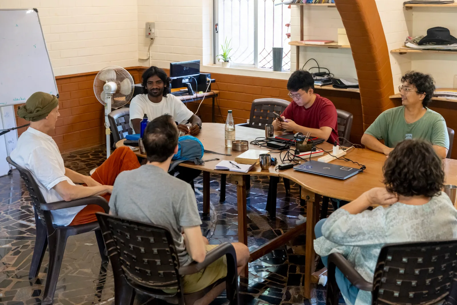 Matthew Binah and Alex in conversation with a partner team around a table in Auroville