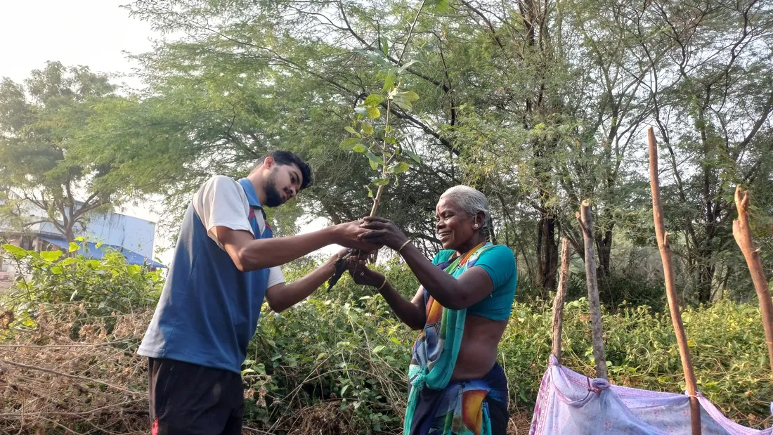 Naeem handing a sapling to a village elder
