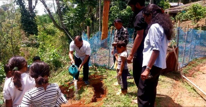 Sandra watering a new tree with children and teachers