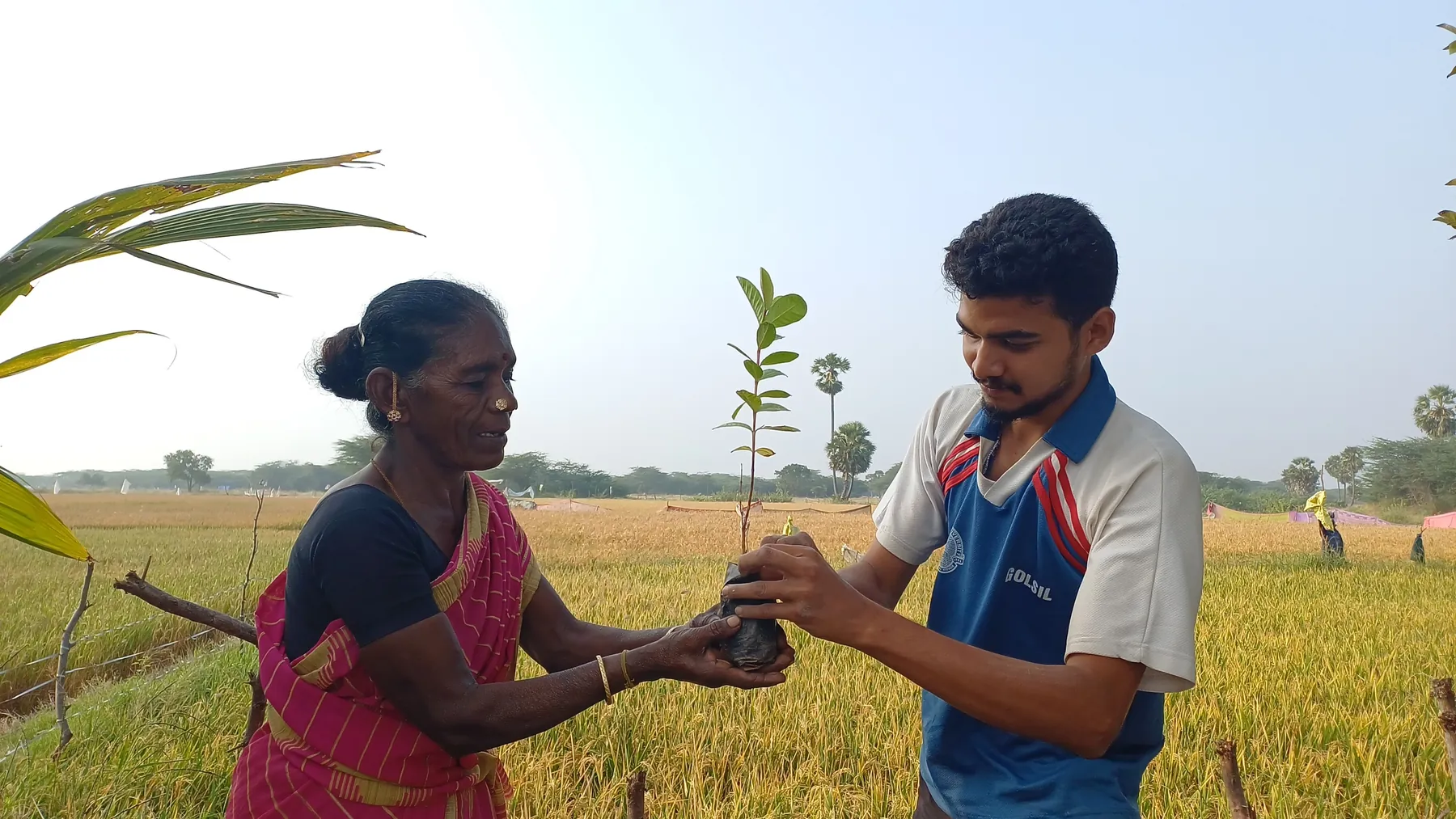Naeem sharing a sapling with a farmer beside the rice fields of Tamil Nadu
